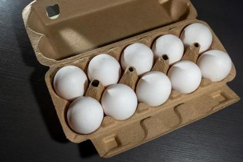 Куриные яйца в картонной упаковке на темной поверхности — продукция птицефабрики