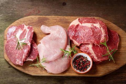 Свежие куски мяса птицы и свинины с приправами на деревянной доске